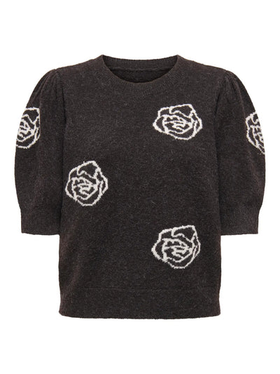Sort pullover med rund hals, hvide blomster på front og ærmer, korte ærmer med puf-effekt.